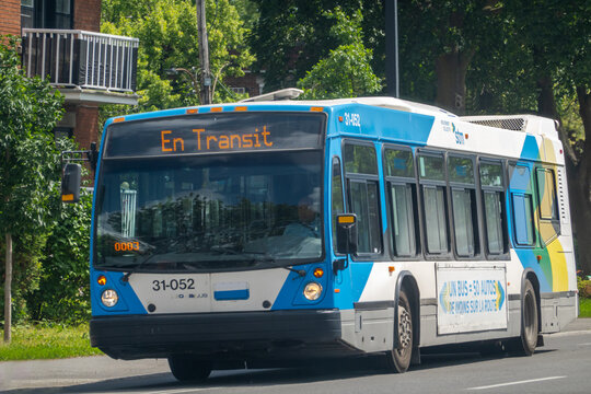 Montreal, Quebec, Canada. July 30, 2026. Blue and white STM city transit bus displaying En Transit on digital sign driving on street.