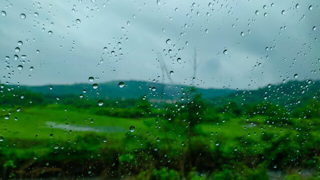 rain drops on a glass of the window of the car in the rainy season.