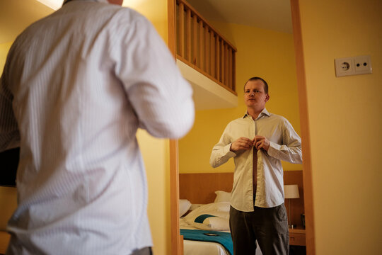 Man getting dressed in shirt preparing for business day