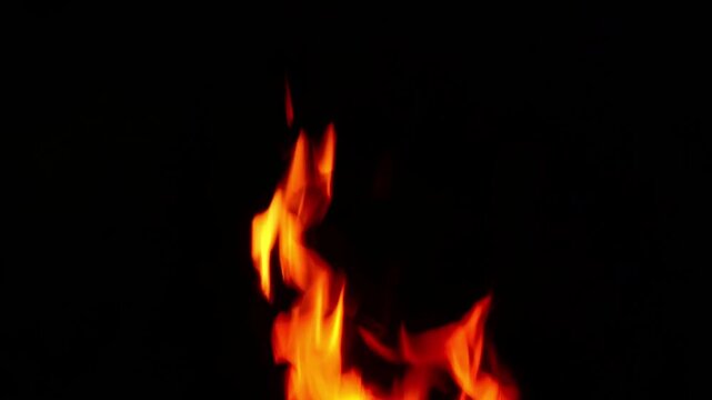 Bright fire flame tongues dancing on pitch black background with natural crackling audio sound. Dynamic motion video background for fiery energy element, hot overlay, visual effects.