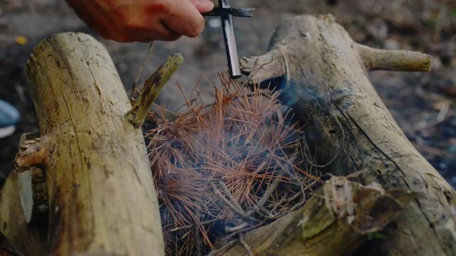Striking ferro rod flint fire starter with knife to ignite campfire with natural audio sound. Close up video of bushcraft survival skills, outdoor fire making technique, spark ignition.