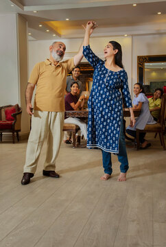 Grandparents dance in the living room in front of the family 