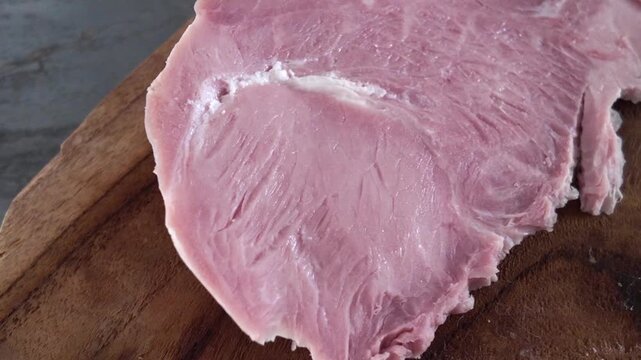 Slicing Cooked Ham - A white man slicing cooked pork ham on a wooden cutting board