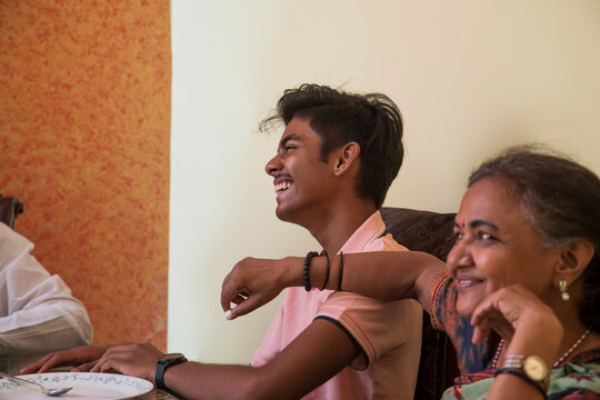 Young boy is smiling with his grandmother on the dining table at home  