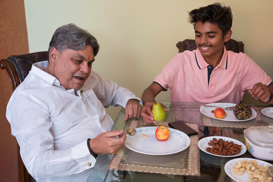 Grandson serving his grandfather on the dining table at home 