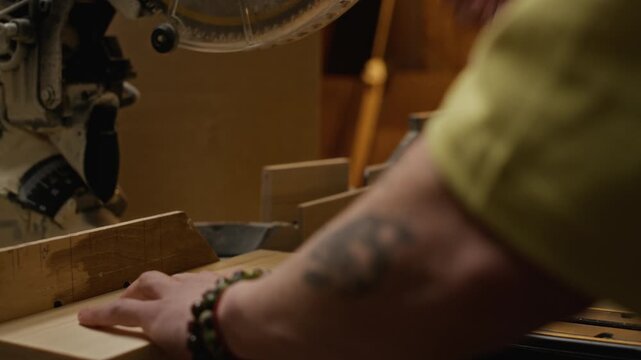 Closeup of carpenter marking wooden plank with pencil, then cutting wood using electric miter saw in workshop. Footage is suitable for woodworking tutorials, DIY brands, and construction promos