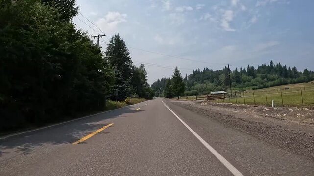 4K smooth stabilized action camera footage driving along scenic rural countryside roads in Washington, USA through evergreen forests, open fields and quiet residential farmland from a driver's p.o.v