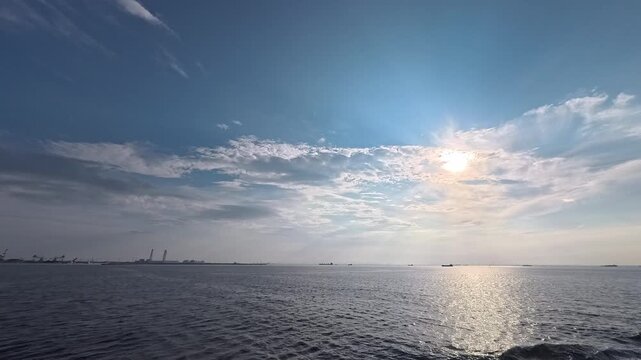 Cinematic real-time video of glistening ocean water surface and dramatic sky with sun rays