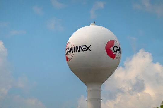 Drummondville, Quebec, Canada. July 30, 2026. Low angle shot of white spherical water tower displaying Canimex logo under blue sky.