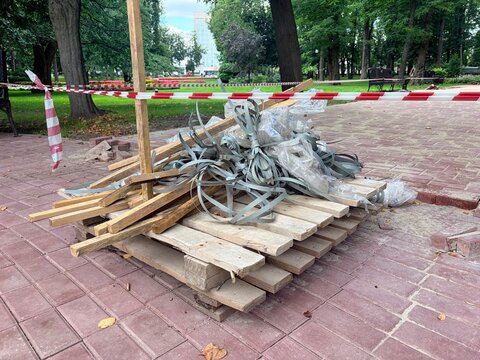 A pile of construction debris is cordoned off with protective tape in a public park