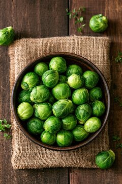 Fresh green brussels sprouts in rustic bowl on wood