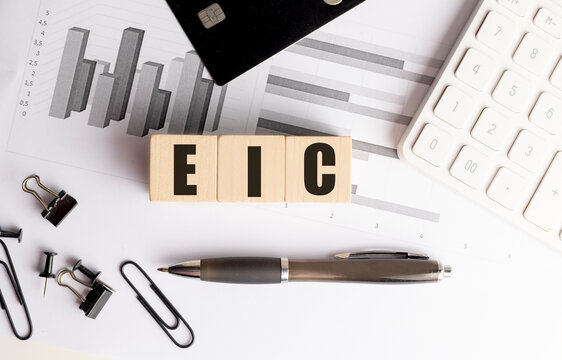 Eic acronym on wooden letter blocks with calculator, credit card and financial charts on office desk