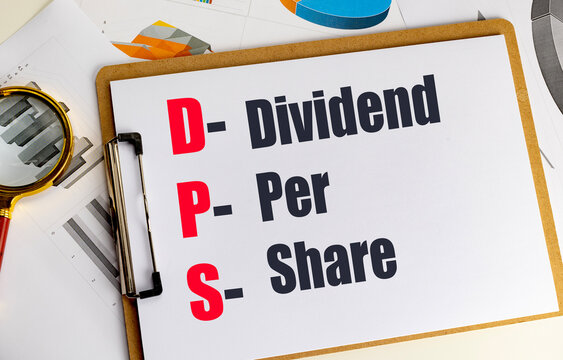 Dividend per share dps acronym on clipboard with magnifying glass and financial charts