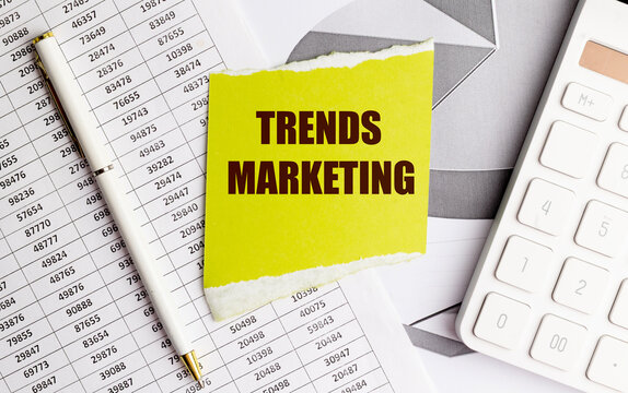 Trends marketing text on torn yellow paper with calculator, charts and financial documents