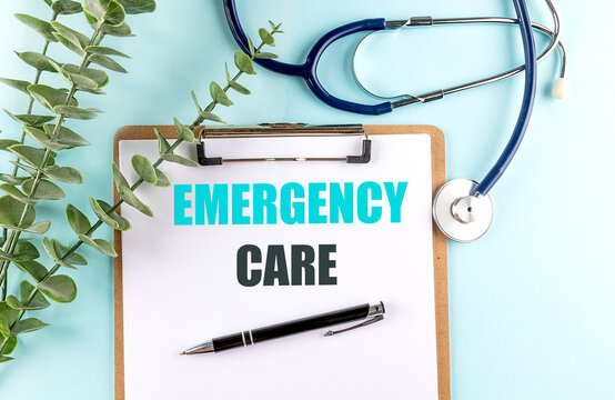 Emergency care text on clipboard with stethoscope, pen and green plant on blue background