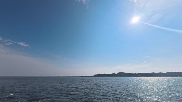 Cinematic real-time video of radiant sun flare over ocean and coastal hills for atmospheric optics