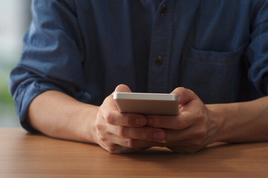 Man using smartphone at table. Watching mobile display.