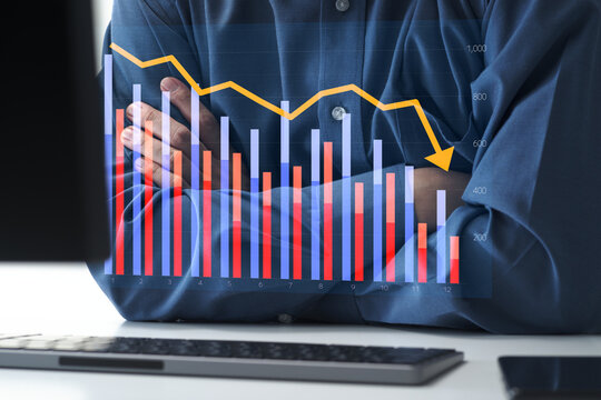 Declining sales and poor business performance. Falling revenue and financial challenges. Businessman looking at graph displayed on computer with crossed arms.