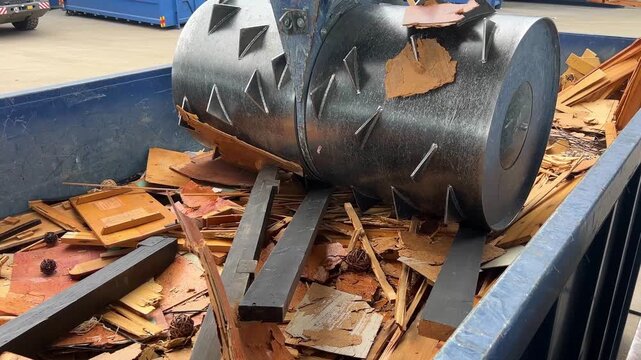 Waste compactor drum crushing wood studs in container for recycling at HWRC