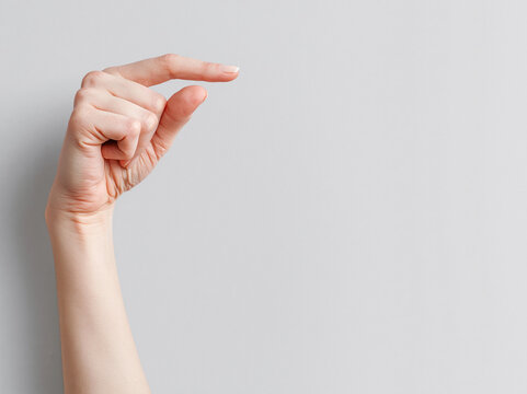 Fingertip Pinch Gesture: A closeup shot captures a hand making a pinching gesture with its thumb and index finger, conveying a sense of smallness or precision.
