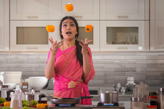woman in kitchen juggling capsicums