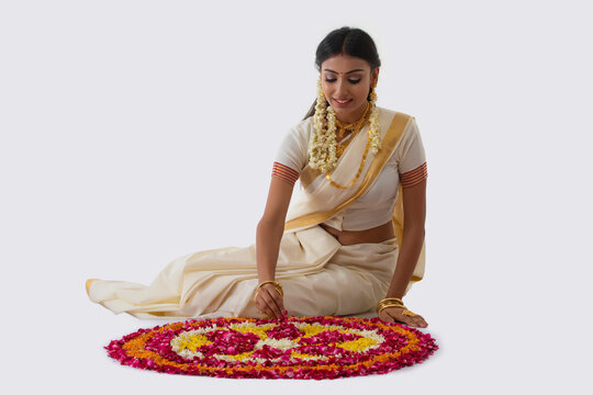 beautiful woman making rangoli with flowers on onam