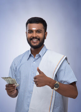 south indian man holding money and smiling at the camera