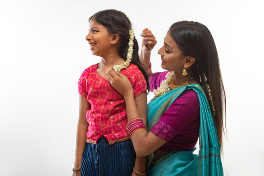 south indian woman putting gajra in her daughters hair