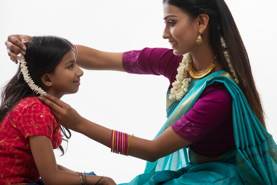 south indian woman putting gajra in her daughters hair