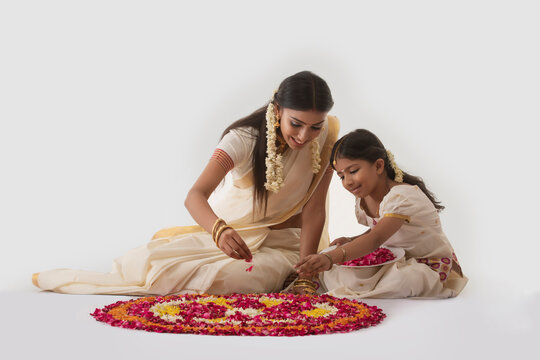 south indian woman making rangoli with her daughter