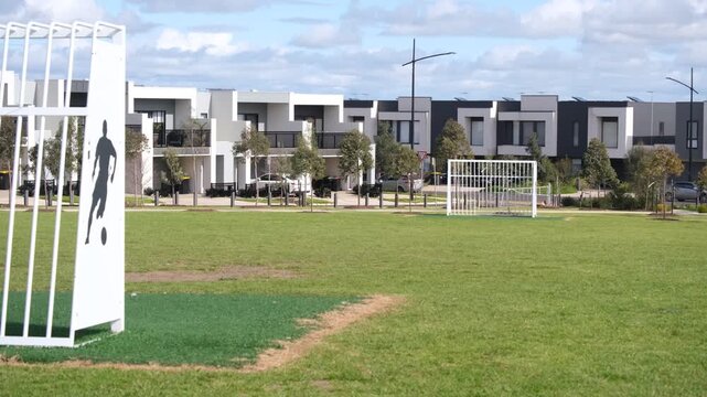 A sports reserve with soccer goals&nbsp;in a modern residential housing estate in Truganina, Melbourne, Australia.&nbsp;Rows of two-storey townhouses and terrace homes behind young street trees in background
