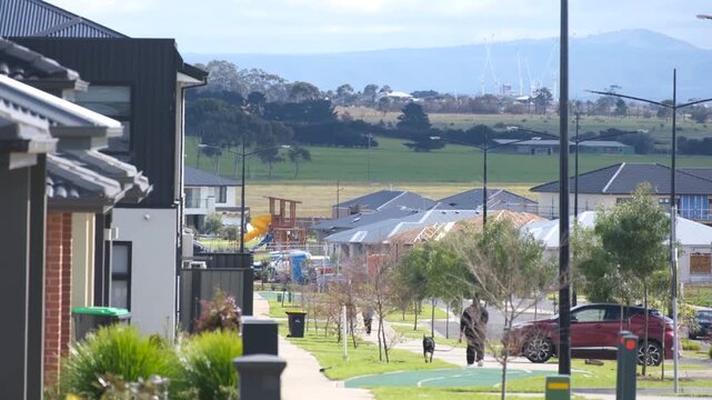 Modern residential street and new housing development near Mt Atkinson, Truganina, Melbourne, Australia. Newly built family homes and young street trees lined the road, open rural plains in background