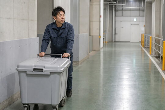 清潔な施設通路で密閉カートを押す廃棄物作業員