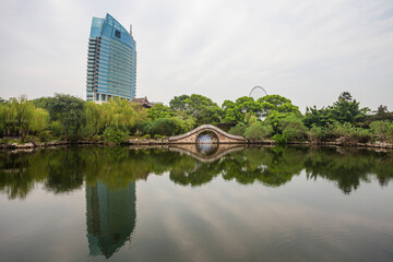 Fototapeta premium Liyuan Park Wuxi - Modern Tower and Traditional Bridge Over Calm Water