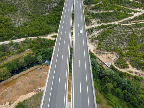Vehicles moving on a high motorway bridge, aerial drone view. Traffic on a modern highway viaduct. Transportation on an elevated dual-carriageway.