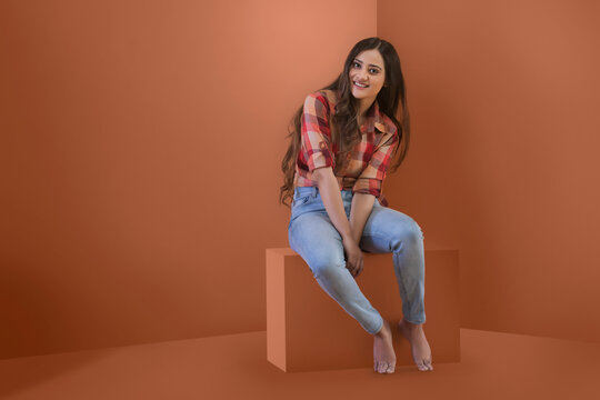 Studio shot of smiling young teenager in jeans posing for photograph