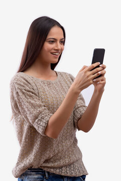 Woman looking at mobile phone standing against white background