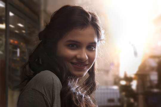 Portrait of a young woman standing outdoors with sunlight in background