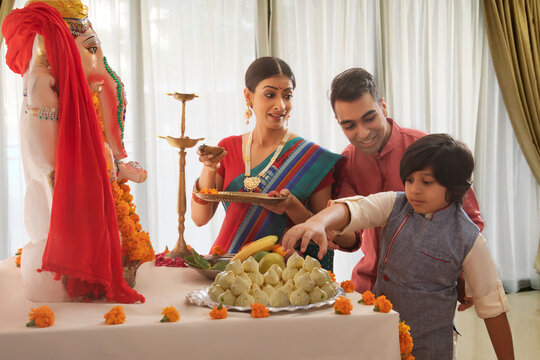 Nuclear family perparing for ganpati pooja where son tries to eat the prasad and the father stops him
