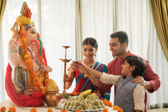 Nuclear family lighting up the diya for Ganpati Pooja on Ganesh chaturthi