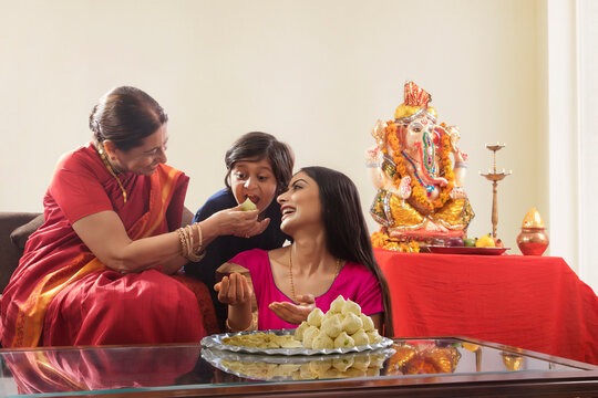 Grandmother feeding her grandson modak on the occasion of Ganesh Chaturthi.