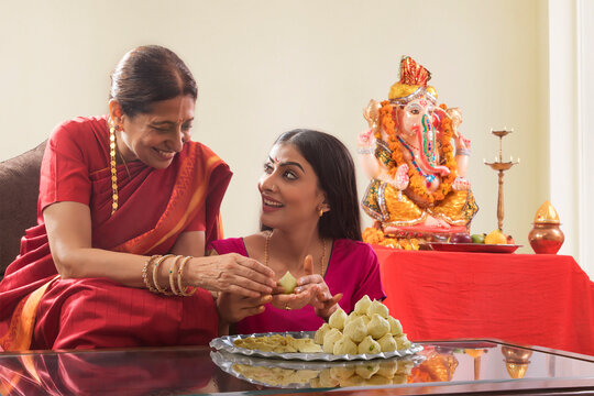Mother in law teaching daughter in law how to make modaks on the occasion of Ganesh Chaturthi