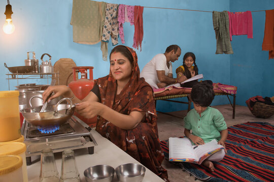 Childs studying in the kitchen while his mother is cooking