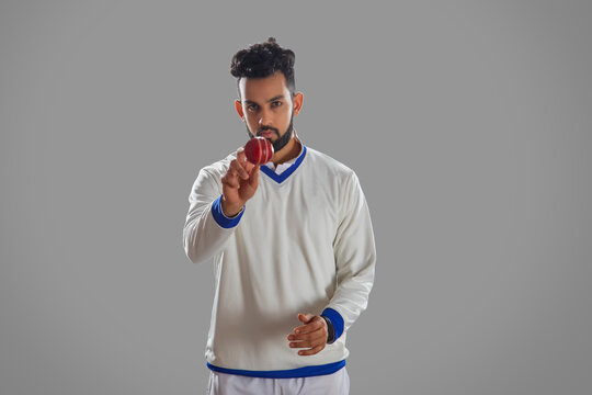 Bowler holding a cricket ball on grey background