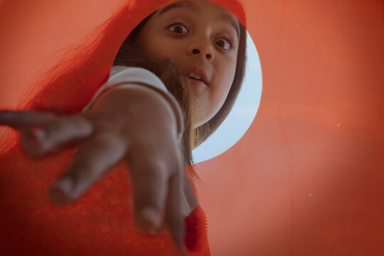 Close up of a girl extending her hand to pick something from an orange container