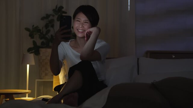 深夜ベッドでスマホを使う女性