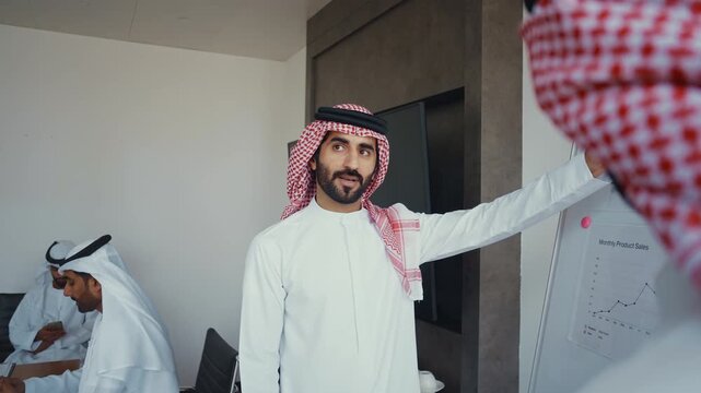Arab businessmen wearing emirati kandura meeting in office for business deal - Corporate business group of middle-eastern people working in an international company in middle east