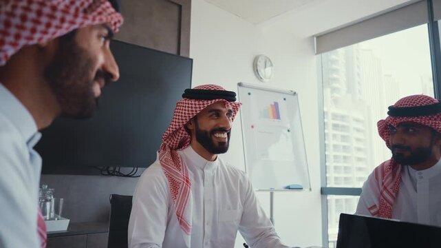 Arab businessmen wearing emirati kandura meeting in office for business deal - Corporate business group of middle-eastern people working in an international company in middle east
