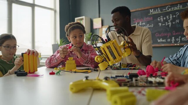 African American male teacher and multiethnic children building robotic models in classroom. Footage is ideal for STEM education marketing and school promotional videos