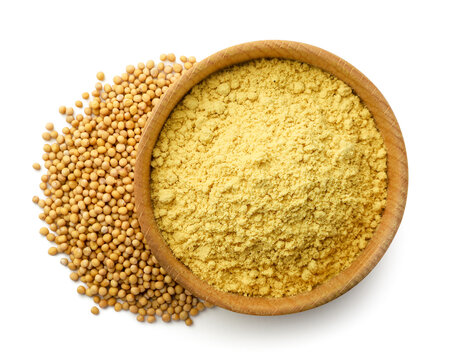 Ground mustard in a wooden bowl and mustard seeds isolated on a white. Top view